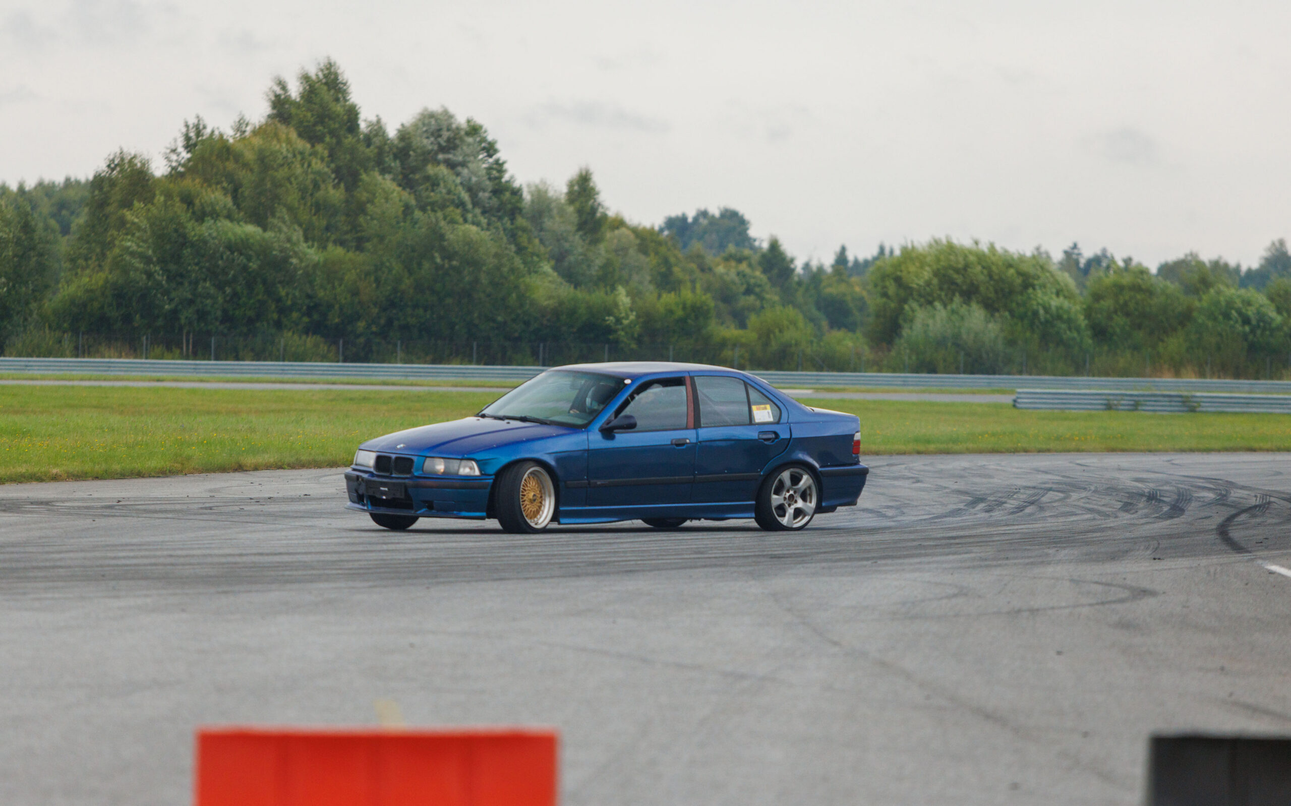 Sinine madaldatud BMW E36 sedaan driftiauto driftimas Porsche Ringi rajal Augustfest 2026 festivalil