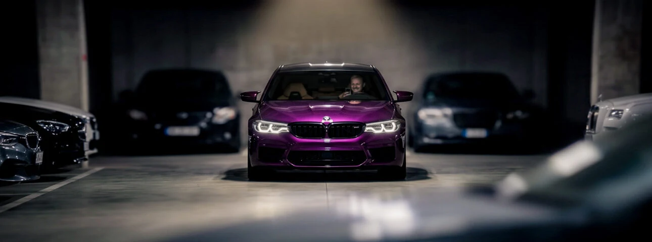 [AI illustratsioon] Reklaamid BMW ekraanil ja lilla BMW M5 F90 sportauto hämaras parklas